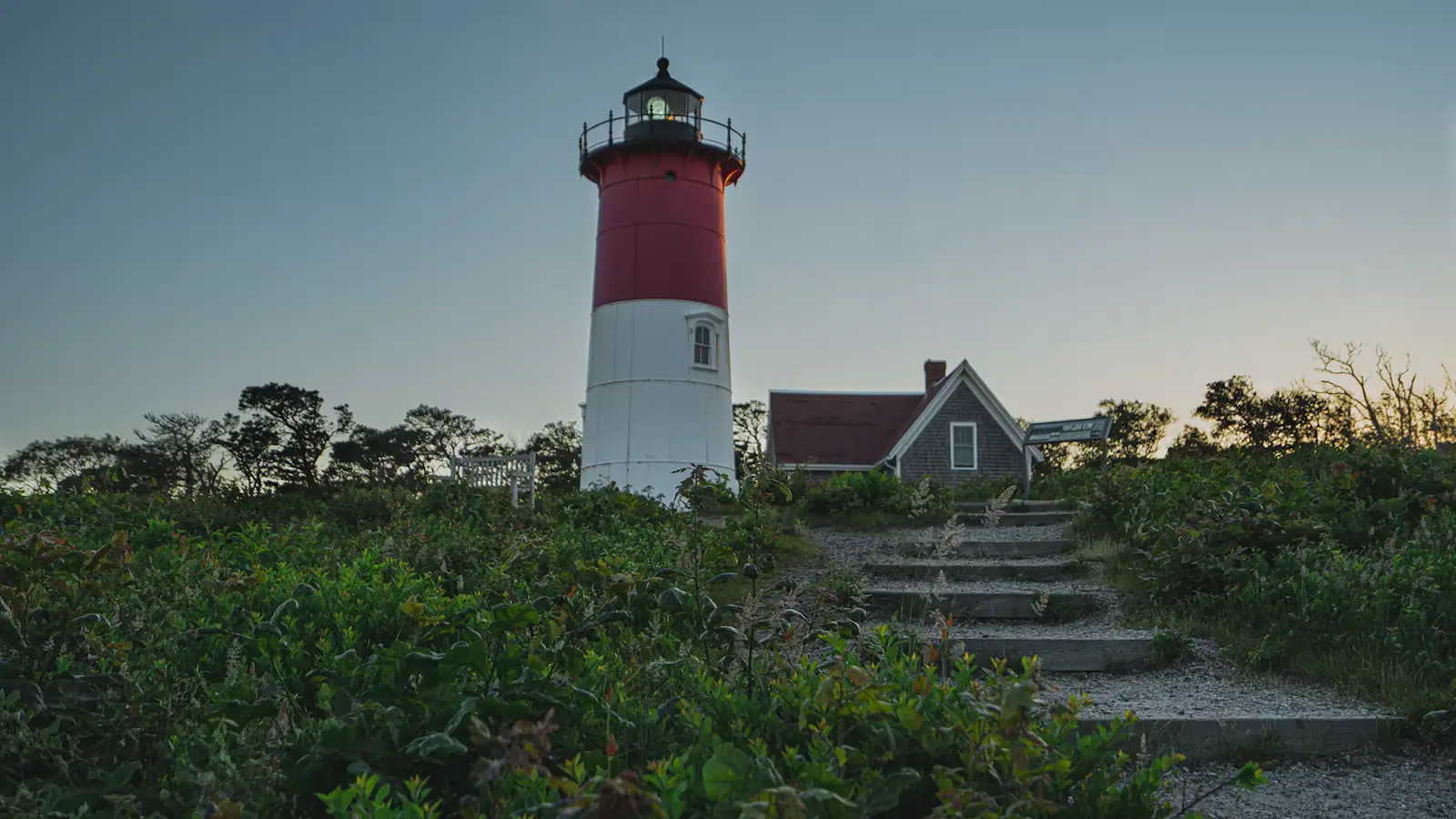 The red and white tower of Nauset Light standing above low trees in Eastham, Massachusetts