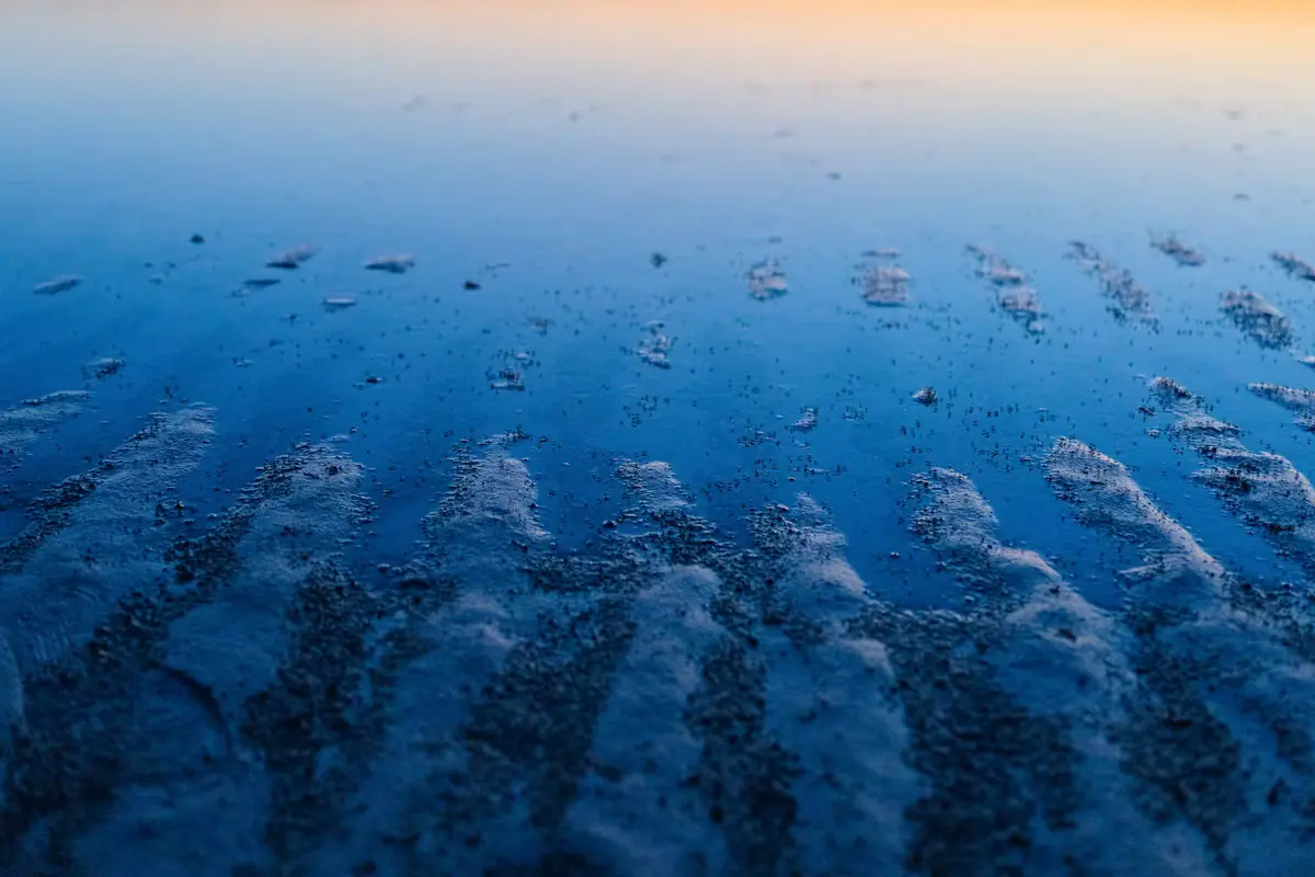 Rows of small waves breaking over shallow offshore sandbars seen from above