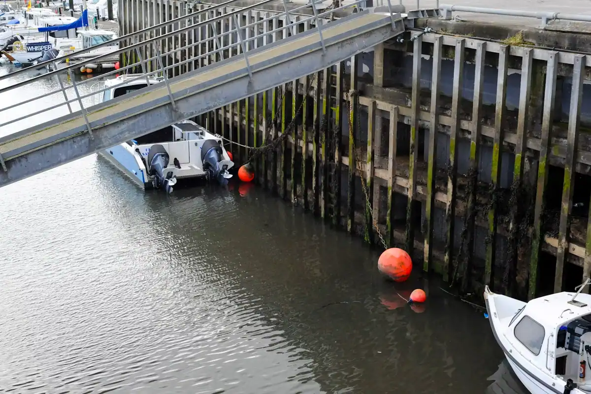 Small boats moored alongside a timber dock and gangway on sheltered water
