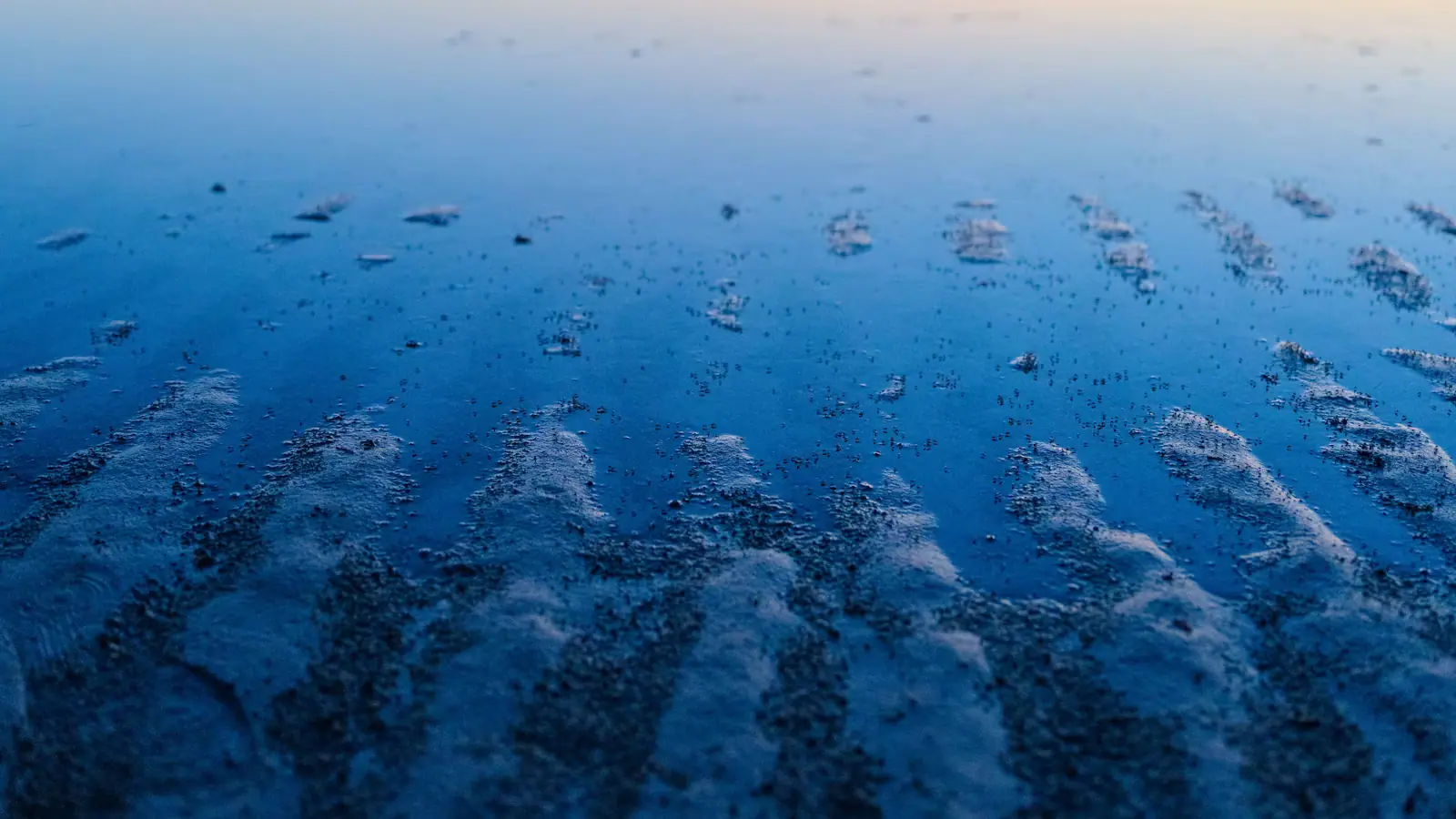 Rows of small waves breaking over shallow offshore sandbars seen from above