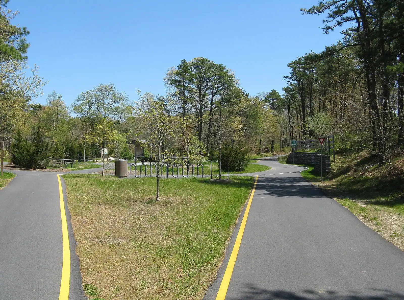 A paved pathway running between green grass under an overcast sky