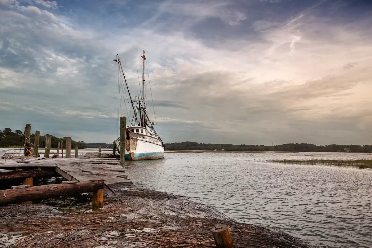 A charter boat tied alongside a floating dock on a still grey morning