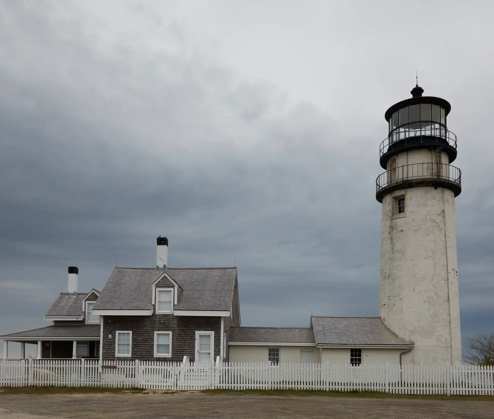 A lighthouse rising above a low building at the water's edge