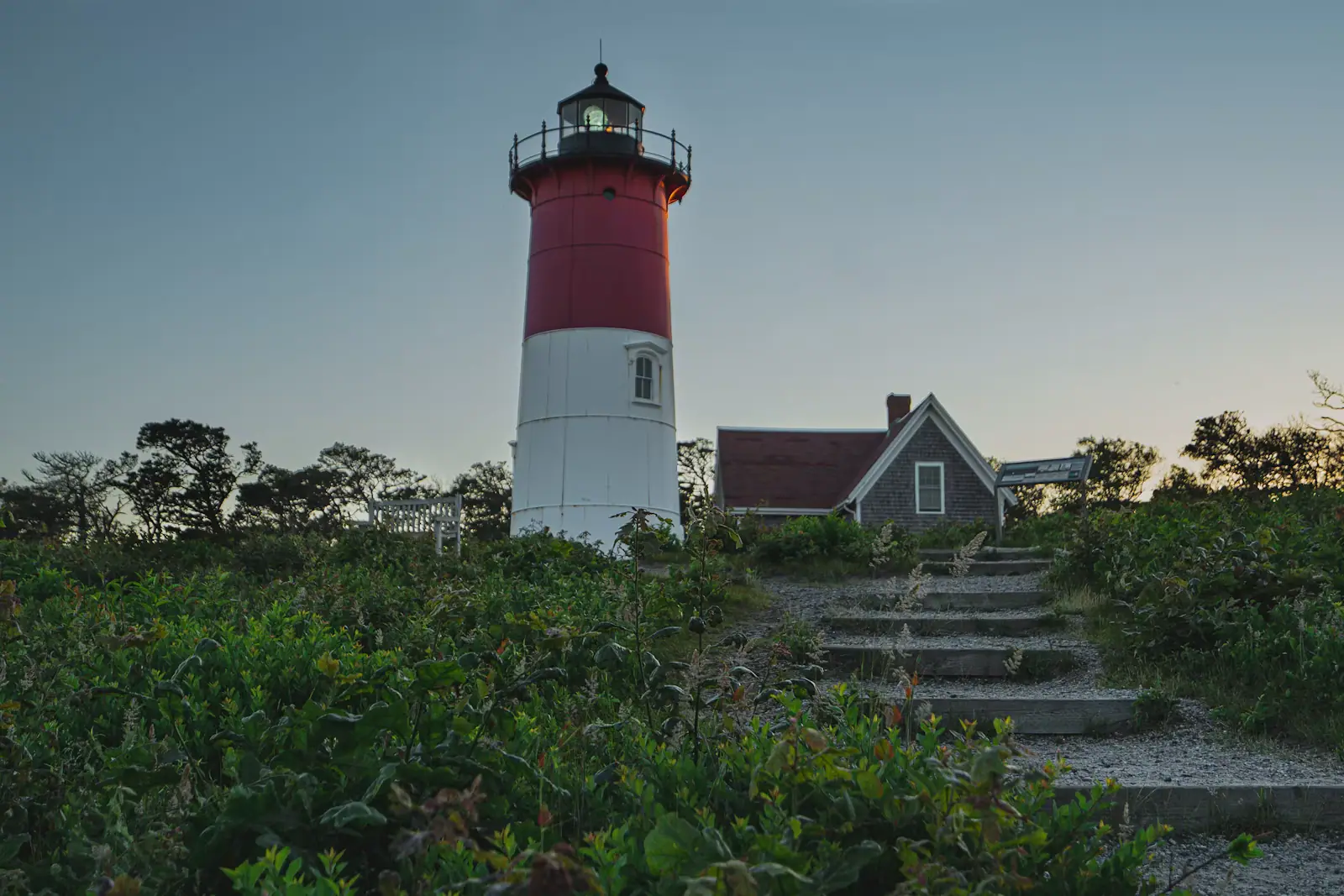 The red and white tower of Nauset Light standing above low trees in Eastham, Massachusetts