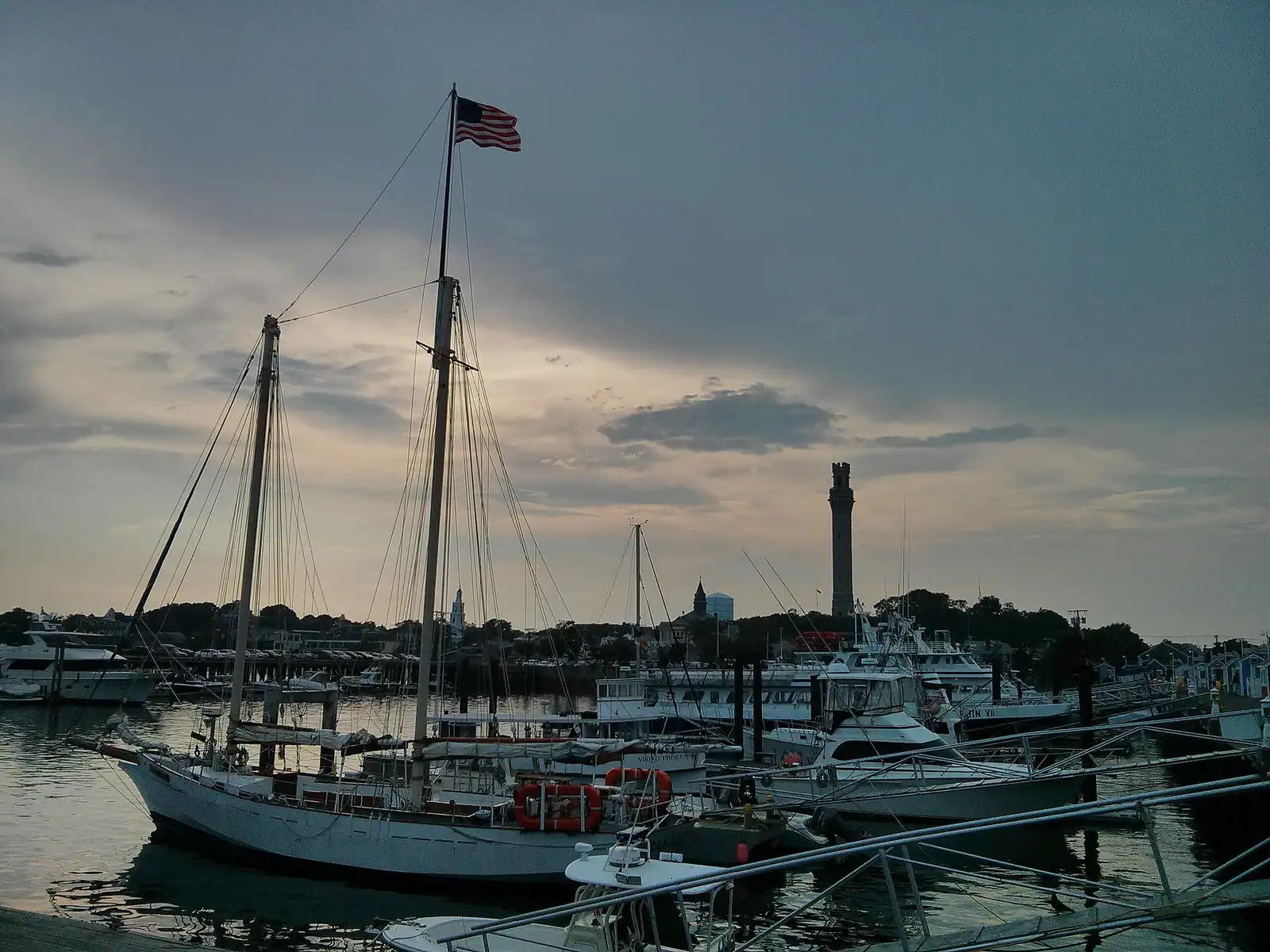 Fishing and excursion boats tied along a pier in Provincetown Harbor with the town behind them
