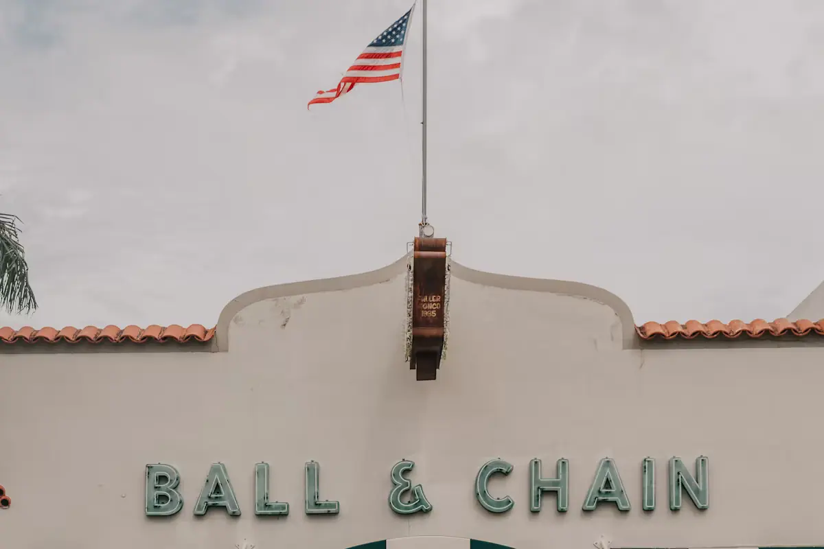 A striped awning and painted lettering above a storefront with a US flag on the wall