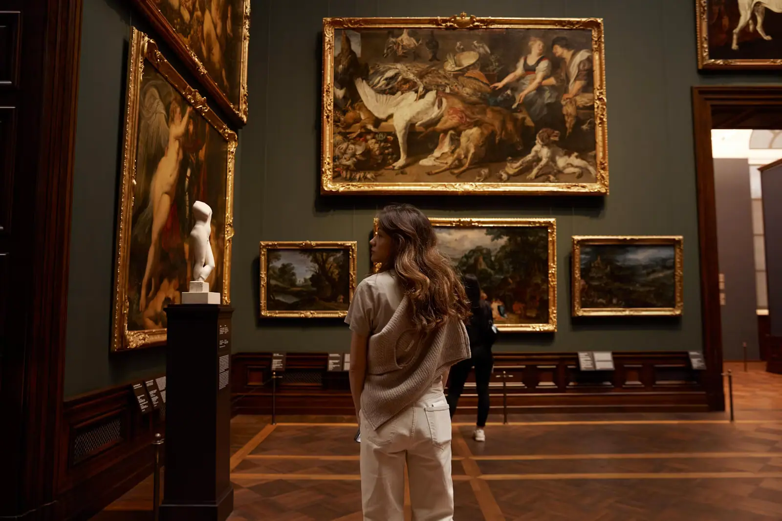 A visitor standing in a gallery looking at exhibits on a white wall