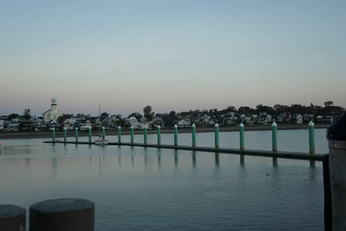 Fishing and excursion boats tied along a pier in Provincetown Harbor with the town behind them