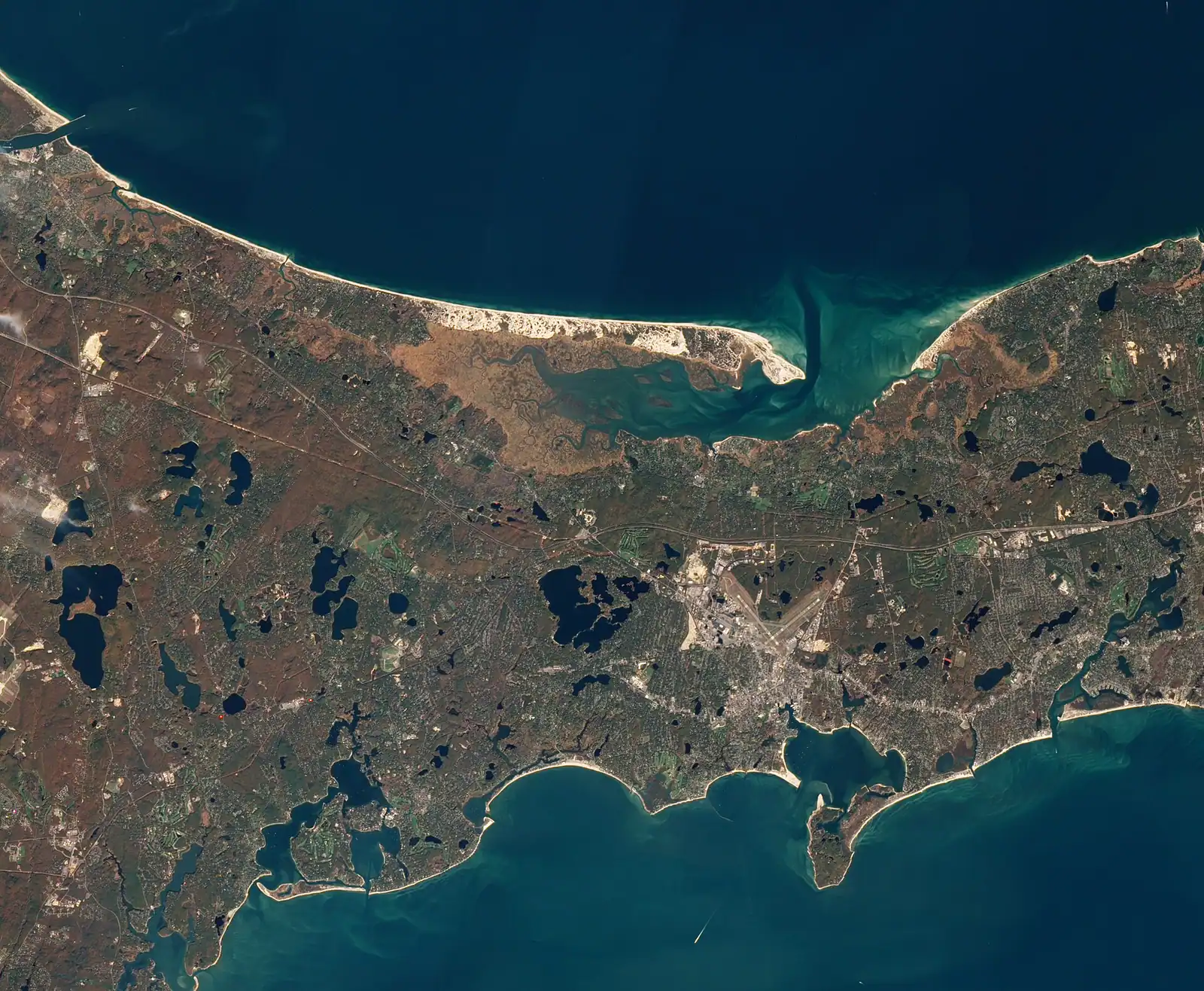 Salt marsh grass and a winding tidal channel under a wide overcast sky on Cape Cod