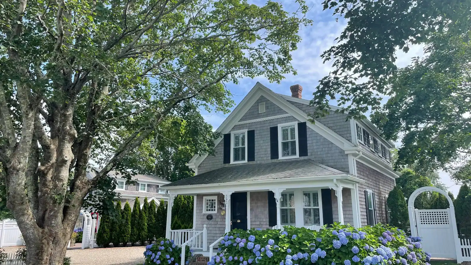 A white and grey shingled wooden house among green trees in Chatham, Massachusetts